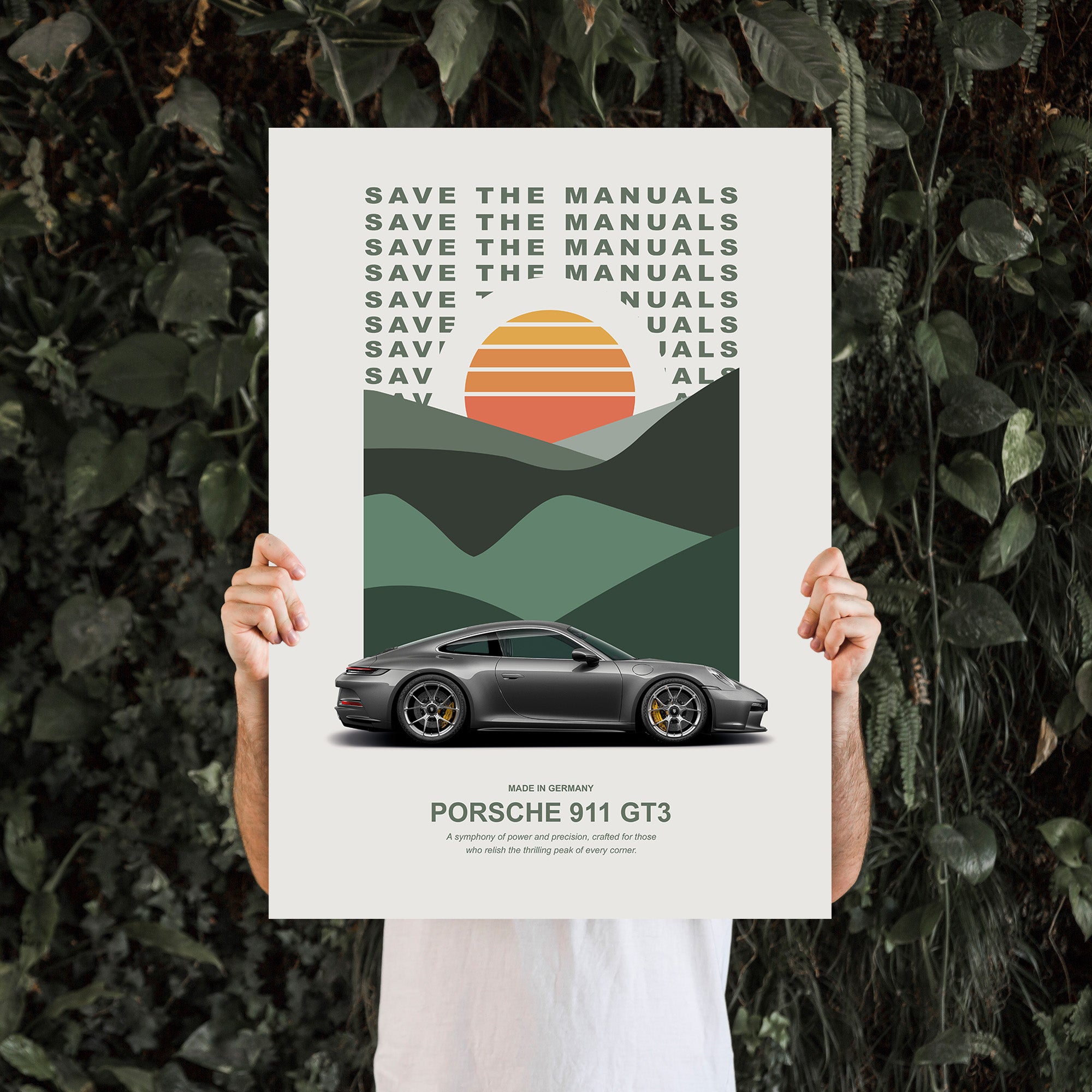 Man holding a Poster with an Porsche on it in front of a plant wall.