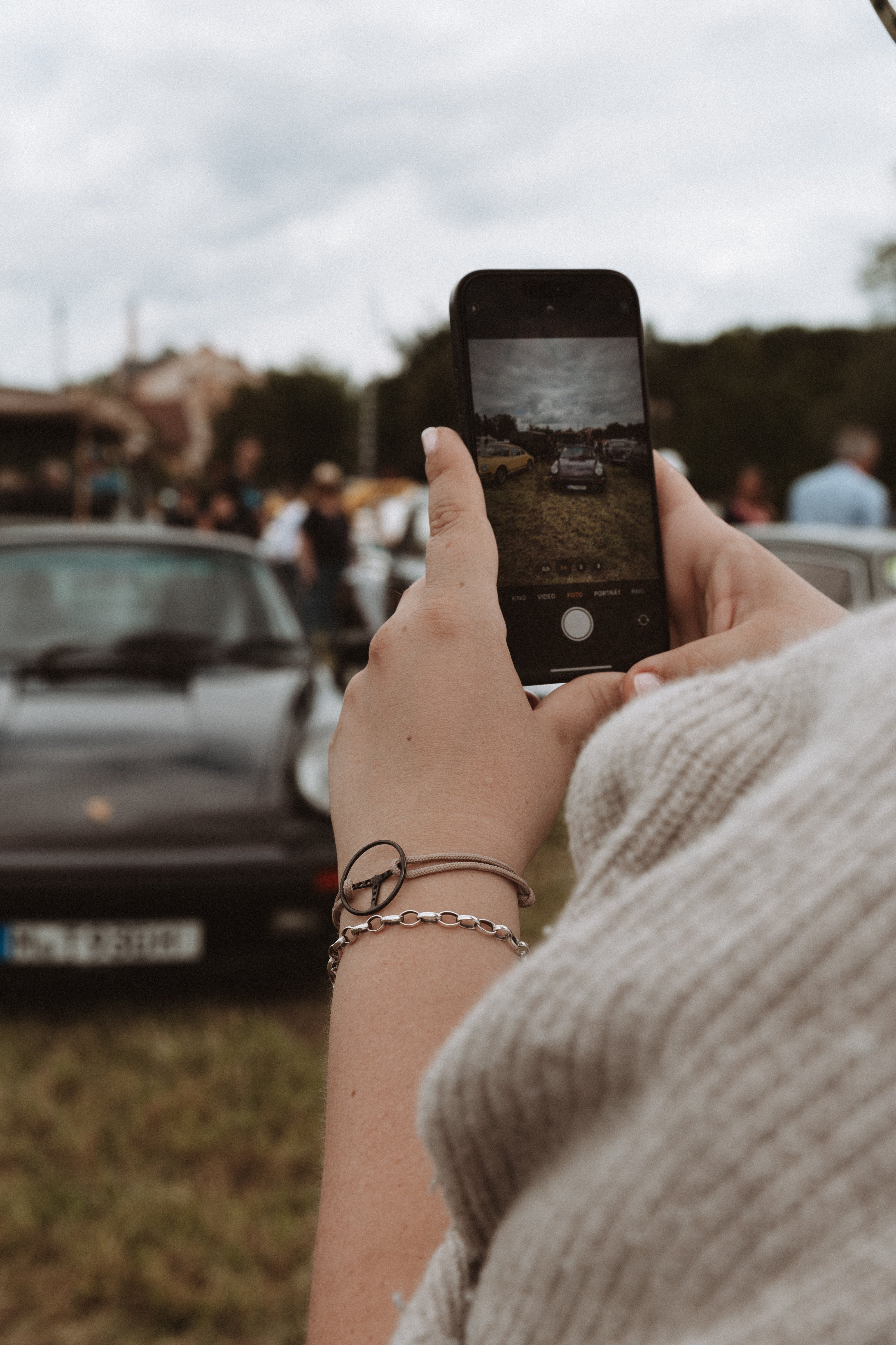 Woman taking a photo of an old Porsche.